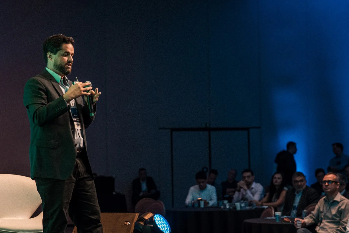 Thomaz palestrando no palco para uma plateia de empresários