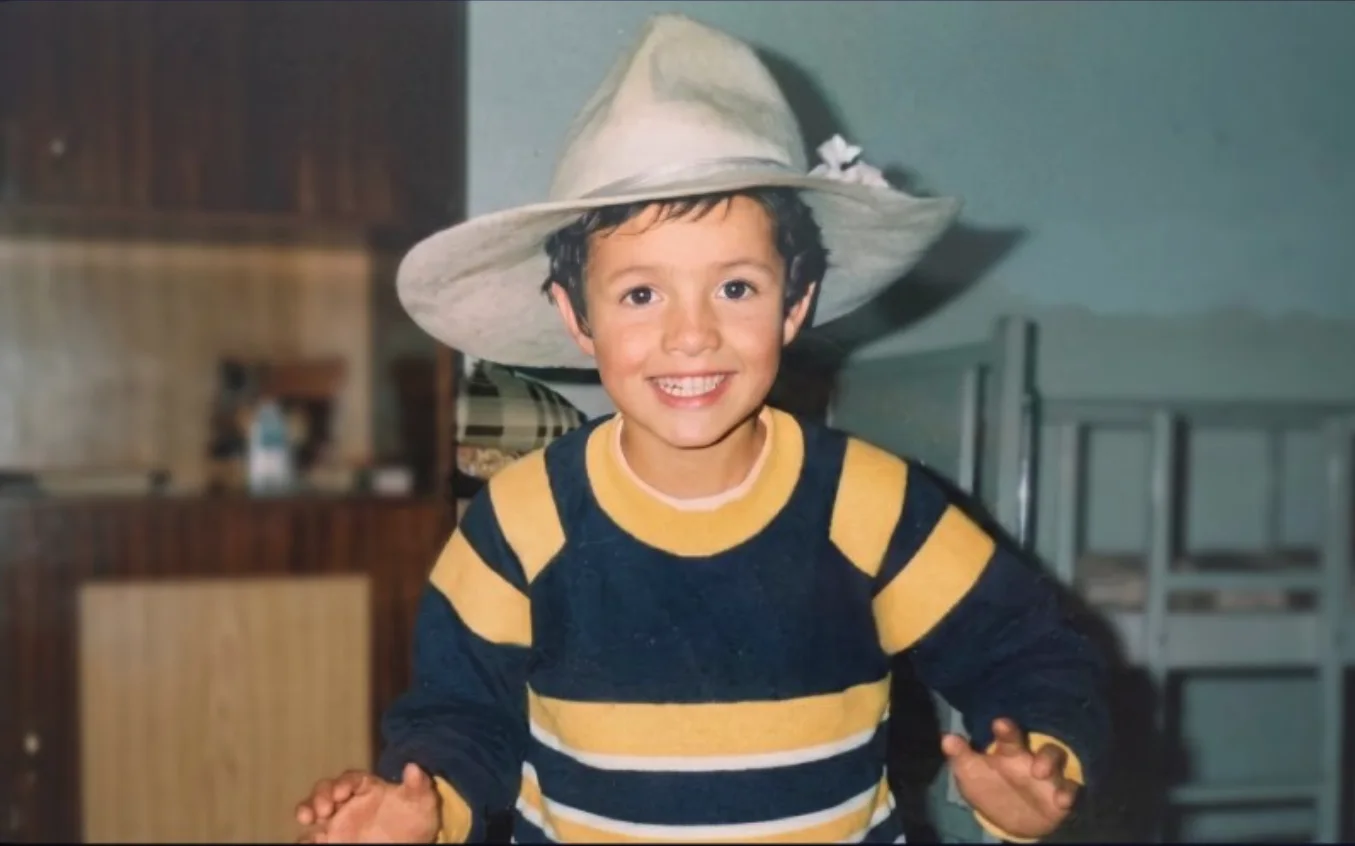 Thomaz criança, de chapéu e blusa listrada, sorrindo